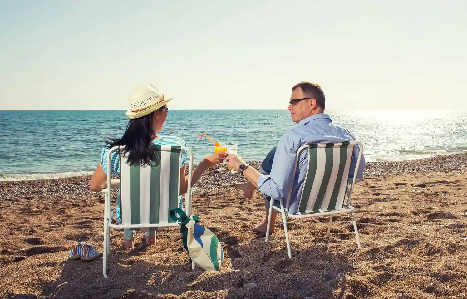 Middle-aged couple relaxing in deck chairs on a sunny beach by the sea.