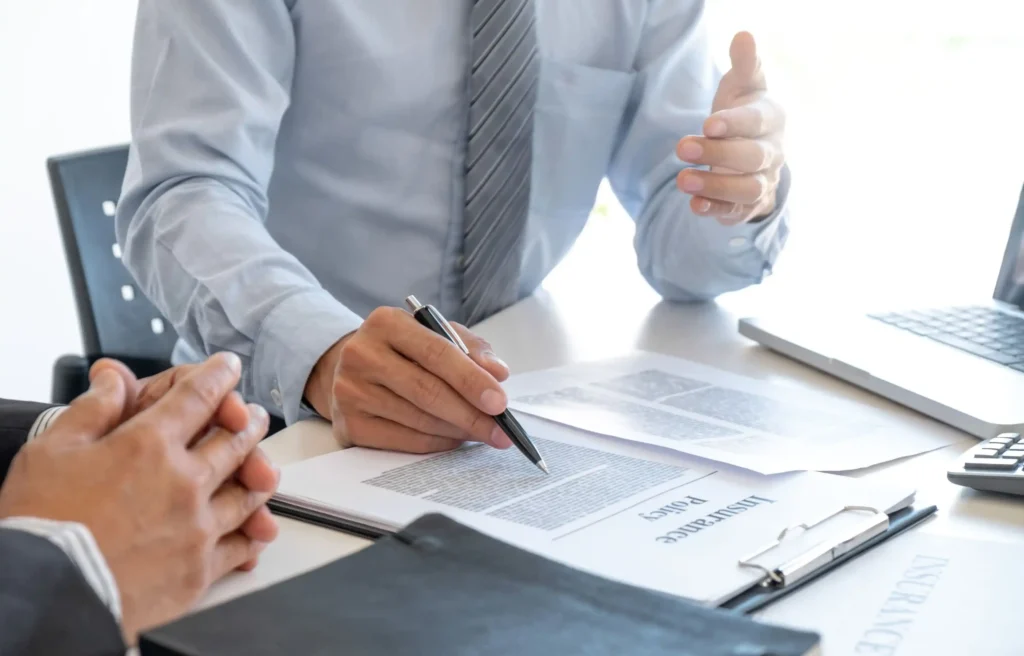 Moving consultant reviewing insurance paperwork and the cost of moving with a client at an office desk.