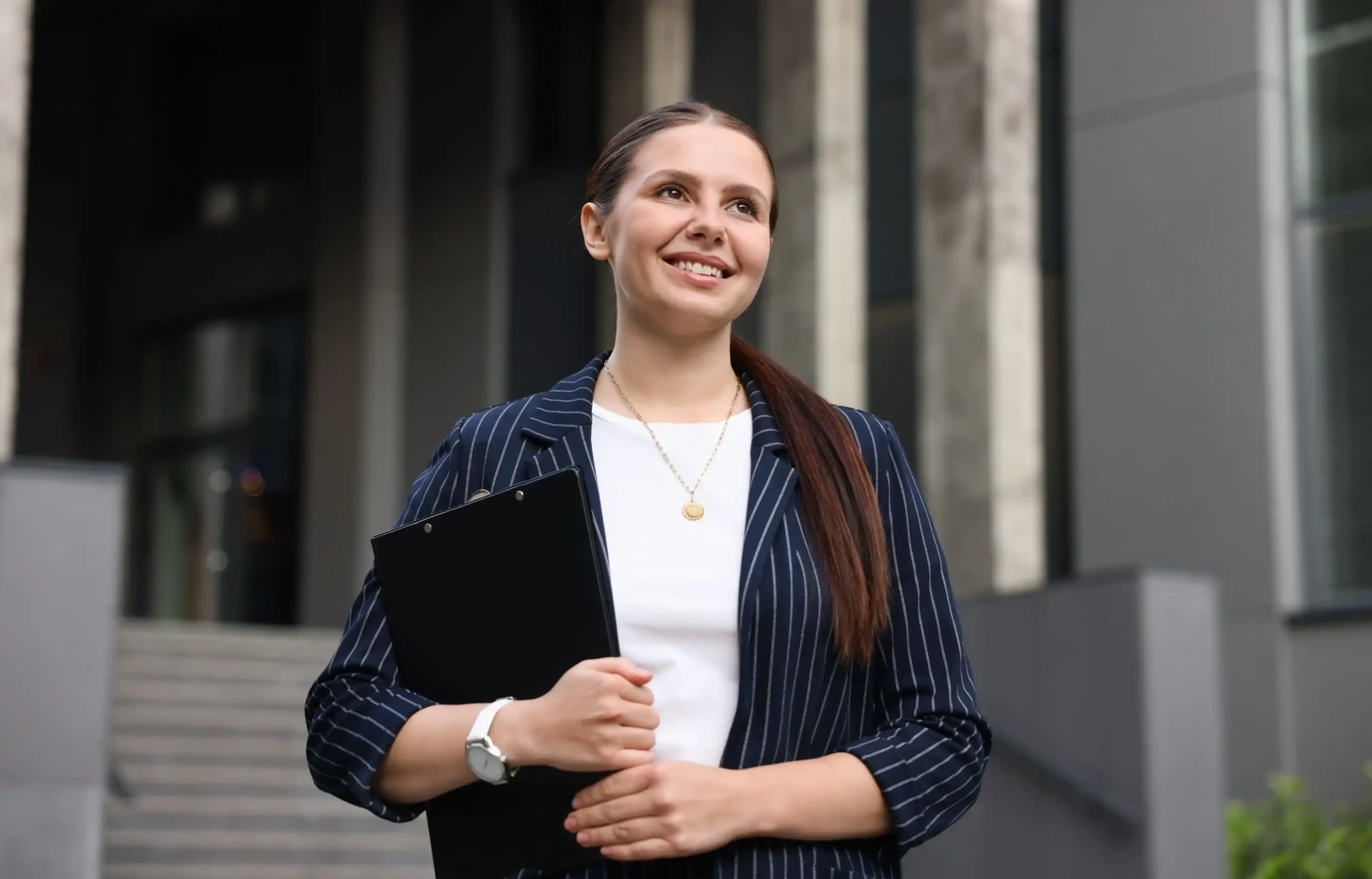 Businesswoman holding a folder outside an office building after receiving a job offer