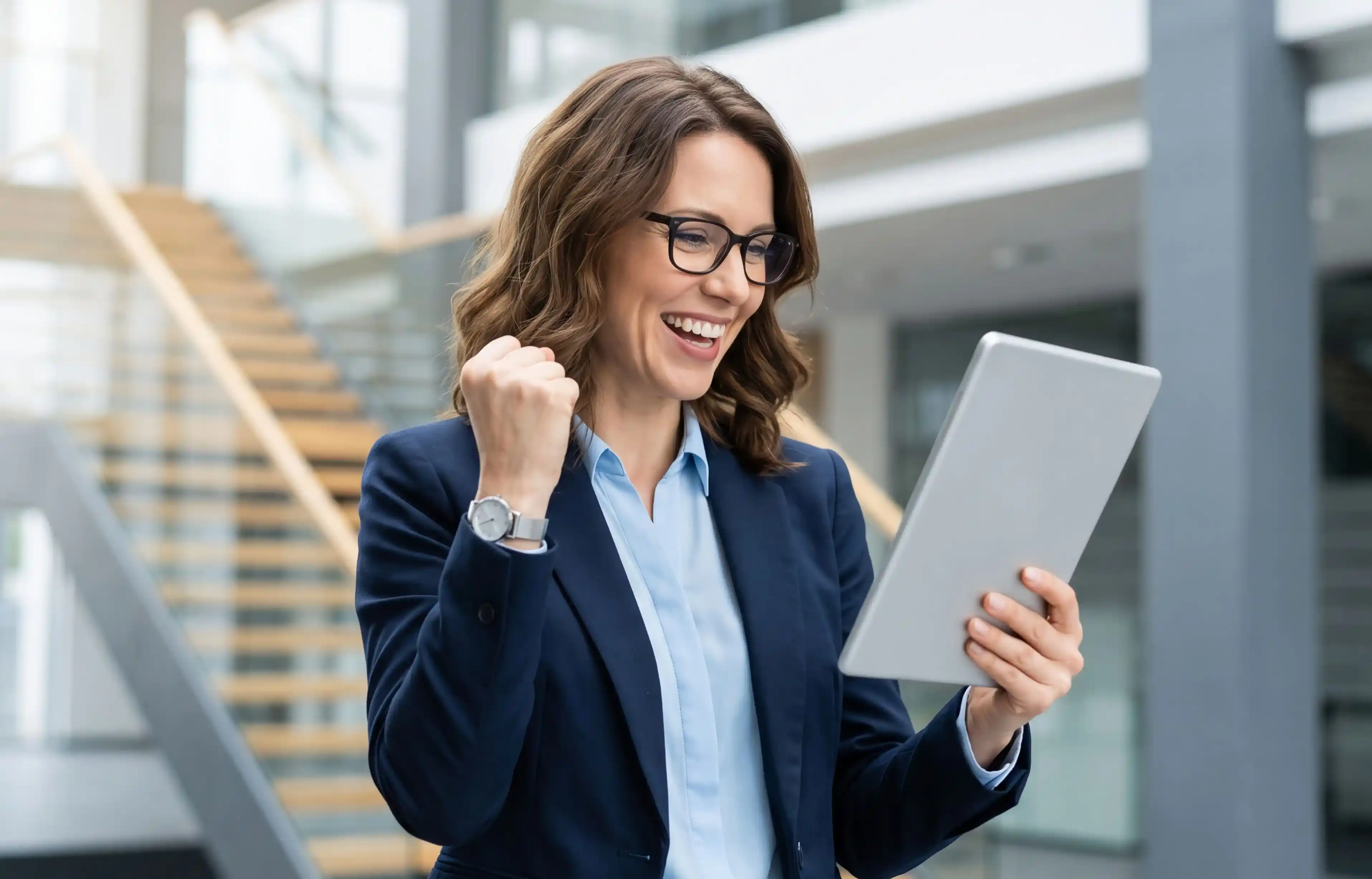 Businesswoman smiling while reviewing relocation details on a tablet in a modern office.
