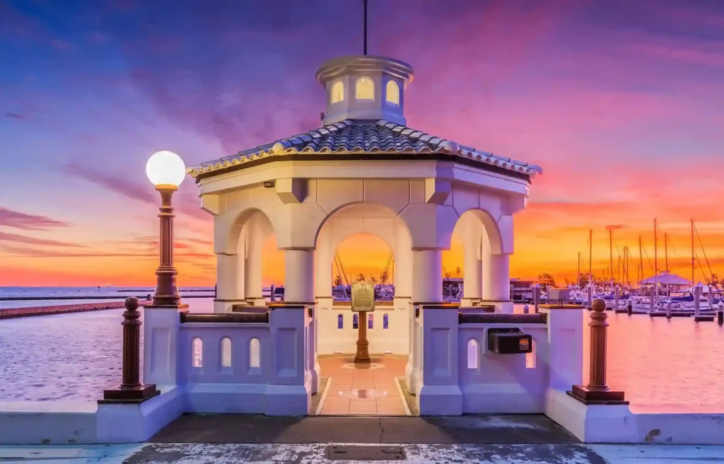 Corpus Christi, Texas waterfront pavilion and marina glowing beneath a colorful sunset sky.