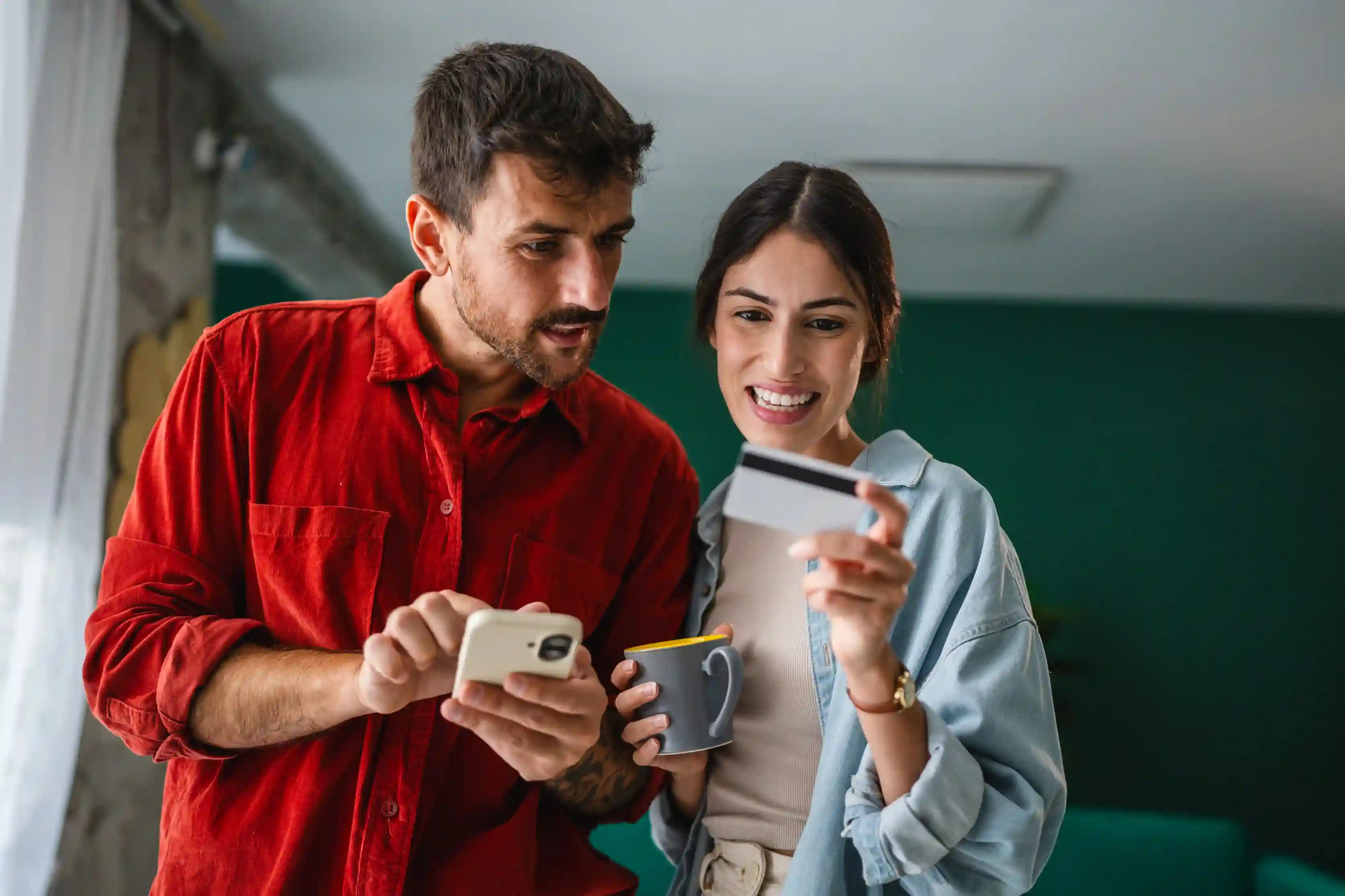 Couple checking a smartphone while holding a credit card to manage moving expenses and rewards.