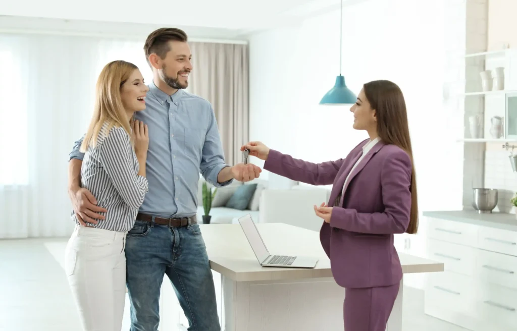 Couple receiving house keys through employee relocation benefits in their new home.