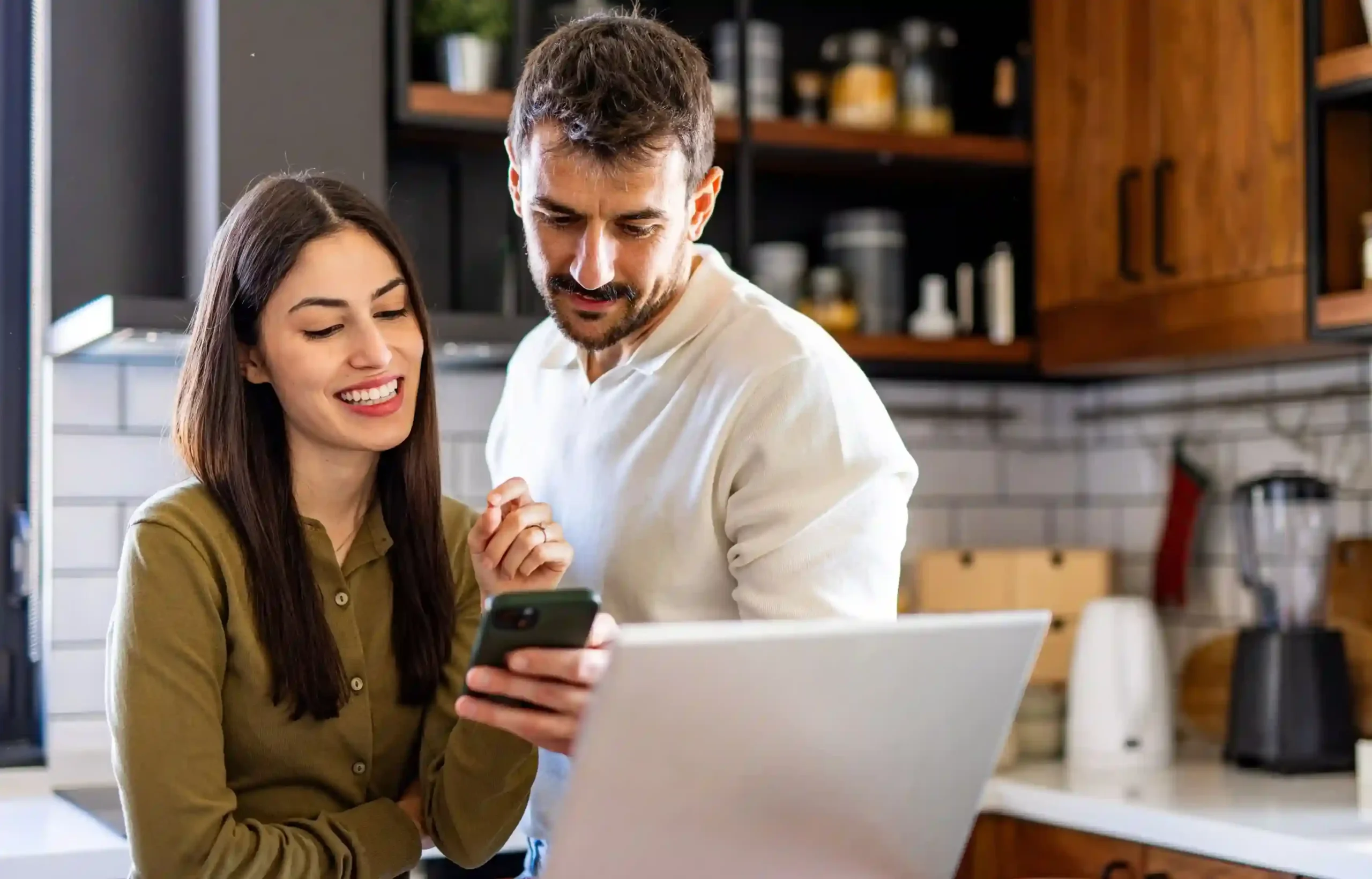Couple reviewing relocation finances together on a laptop and smartphone at home.