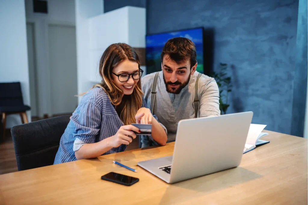 Couple using a laptop and credit card to plan moving expenses and earn credit card rewards.
