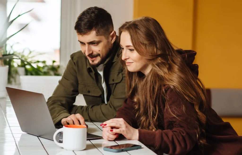 Digital nomad couple comparing genki vs safetywing insurance on a laptop while planning their digital nomad journey.