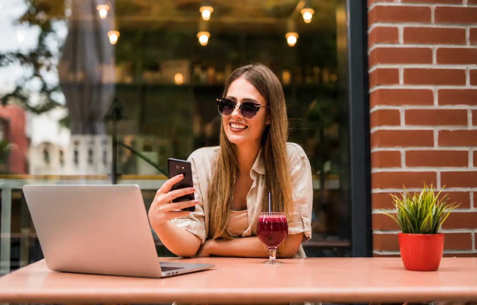 Digital nomad woman using a laptop and smartphone at an outdoor café.