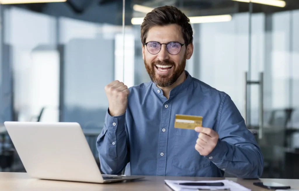 Employee using credit card strategies for employees to manage relocation expenses beside a laptop.