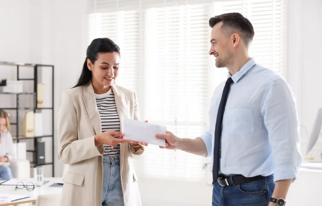 Employee moving for a job receives an offer letter from a manager in a modern office.