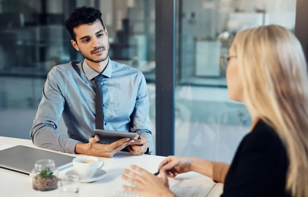 Employee reviews relocation terms to negotiate layoff protection with an HR representative during an office meeting.