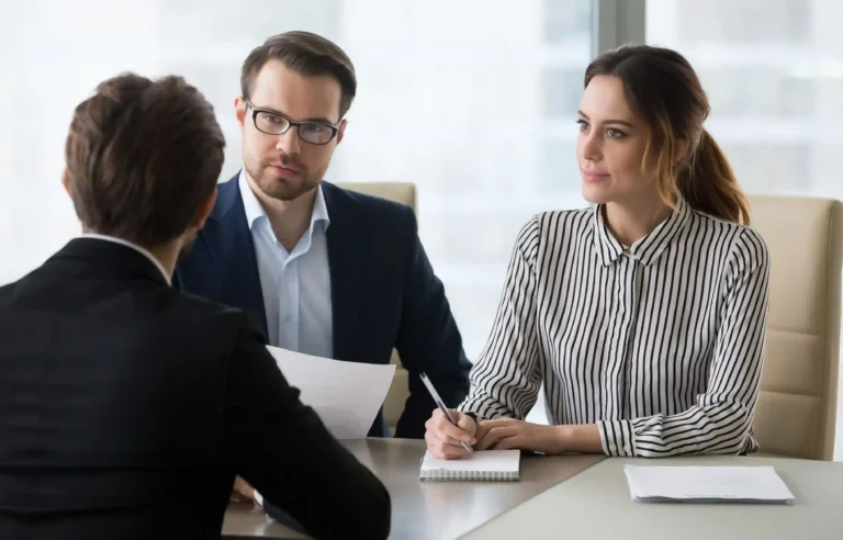 Employees discuss a relocation offer and layoff protection terms during a meeting.