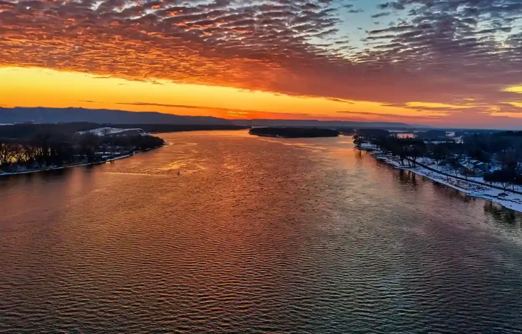 Gulfport, Mississippi coastal water and shoreline glowing beneath a vivid orange sunset.