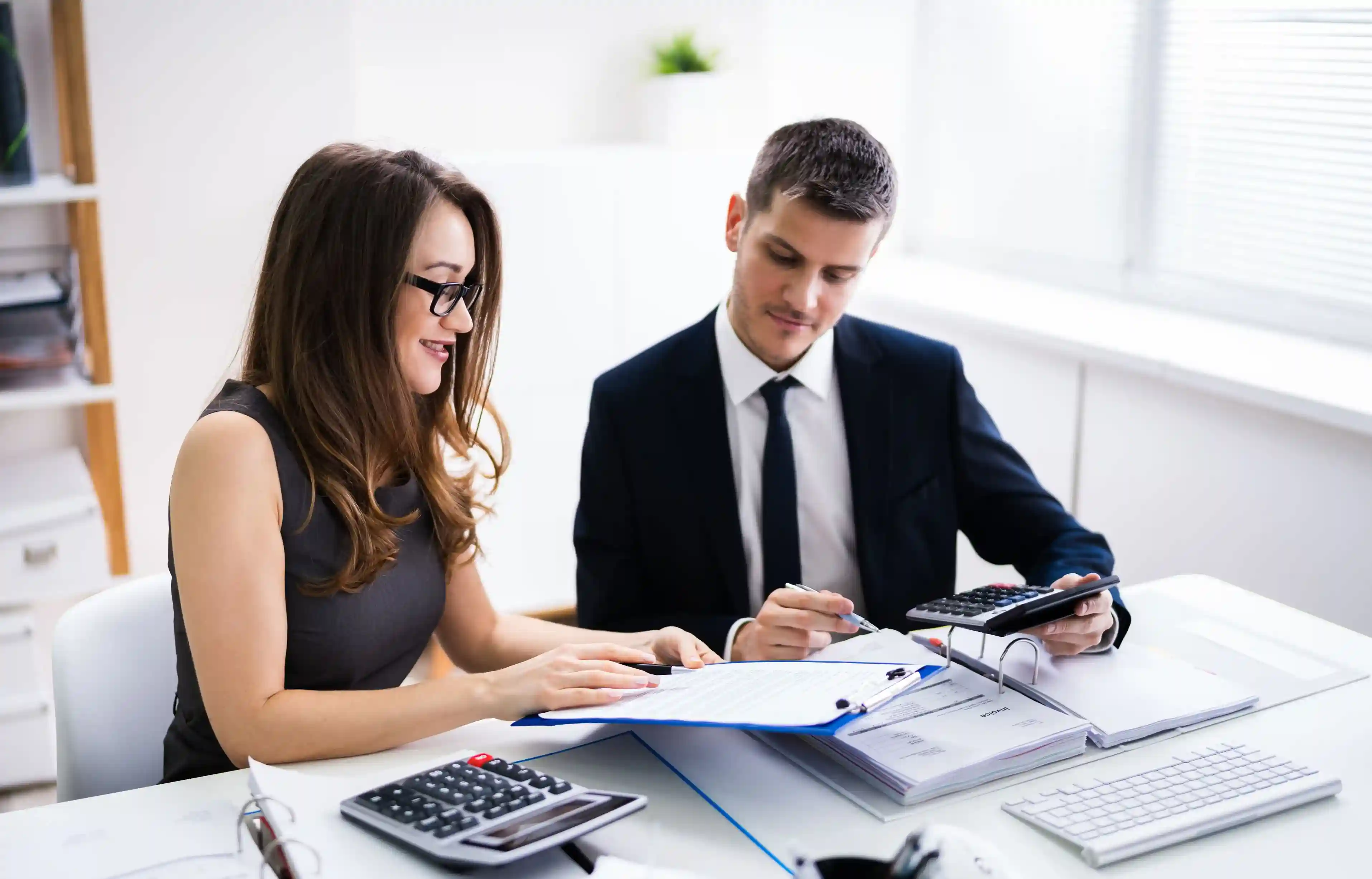HR and finance professionals reviewing relocation costs and policy documents with calculators.
