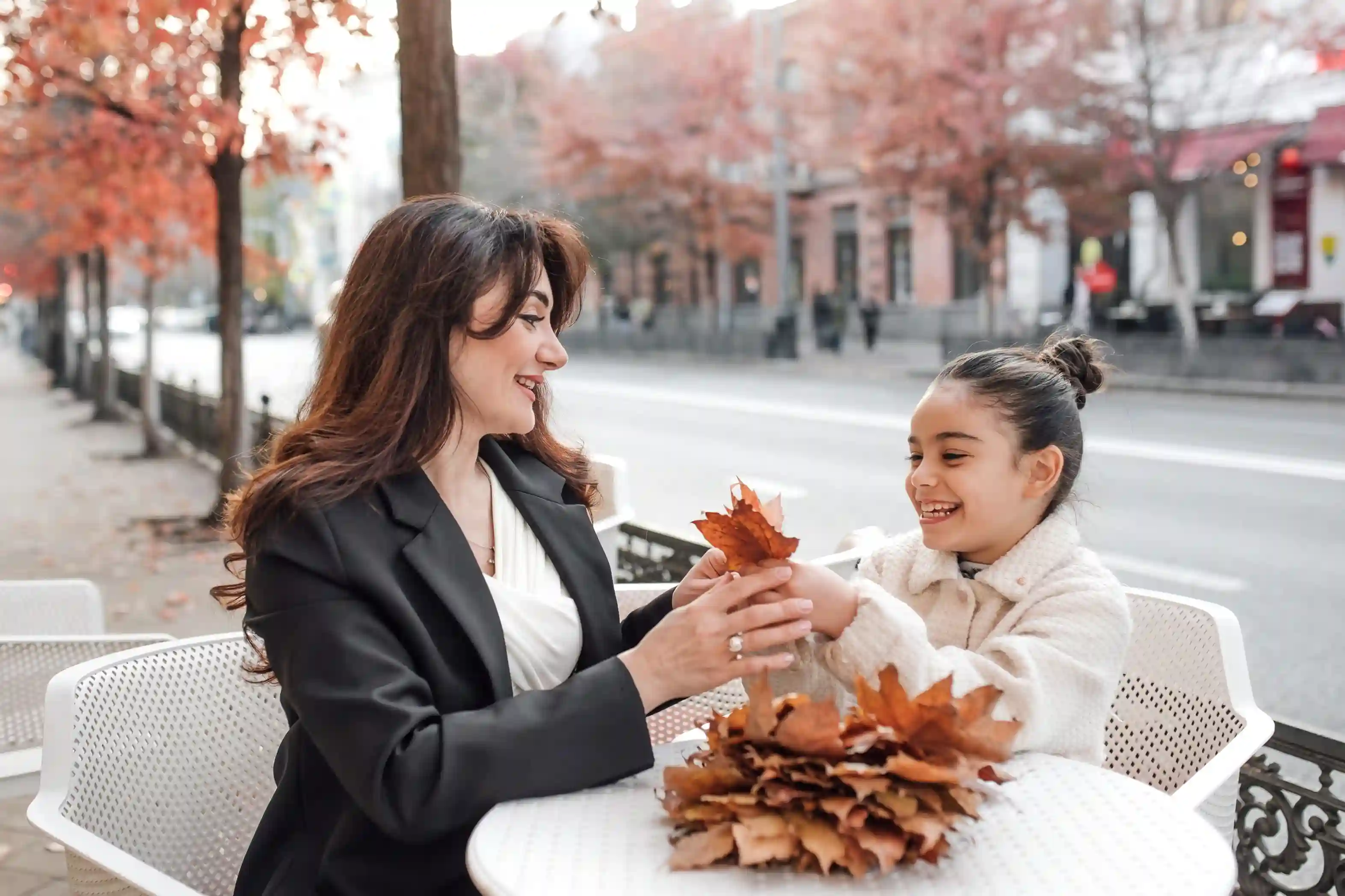 Mother and daughter enjoying autumn leaves together during a family relocation outing.