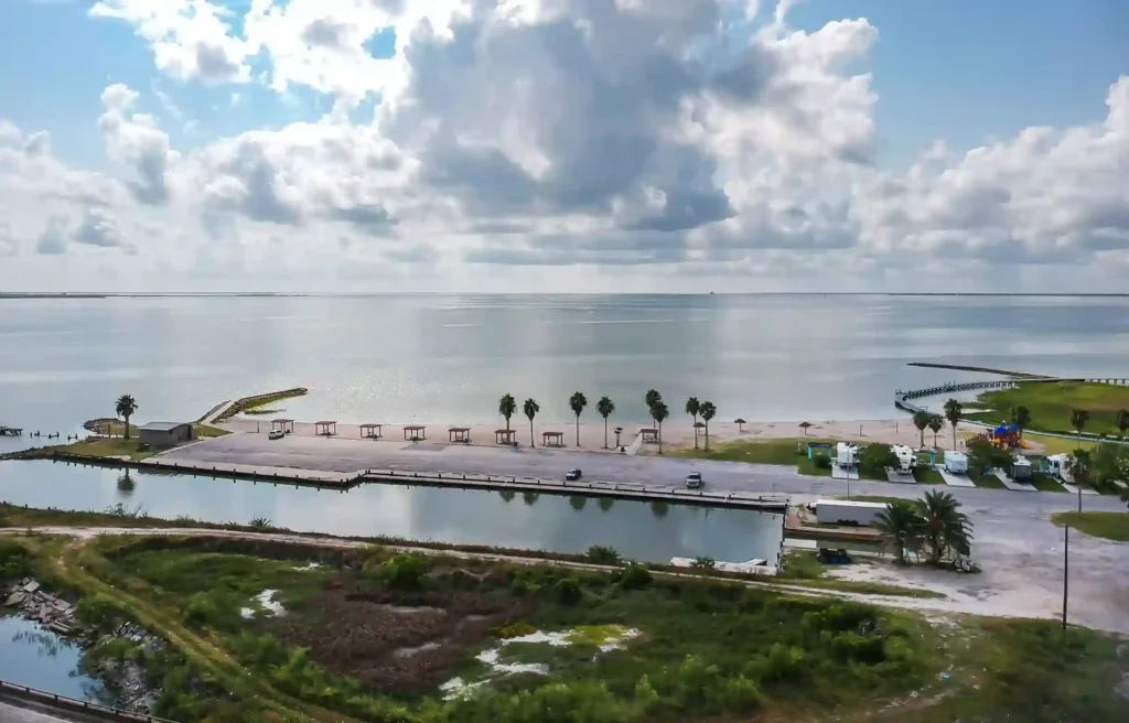 Port Lavaca, Texas waterfront park with palm trees, calm bay water, and a cloudy blue sky.