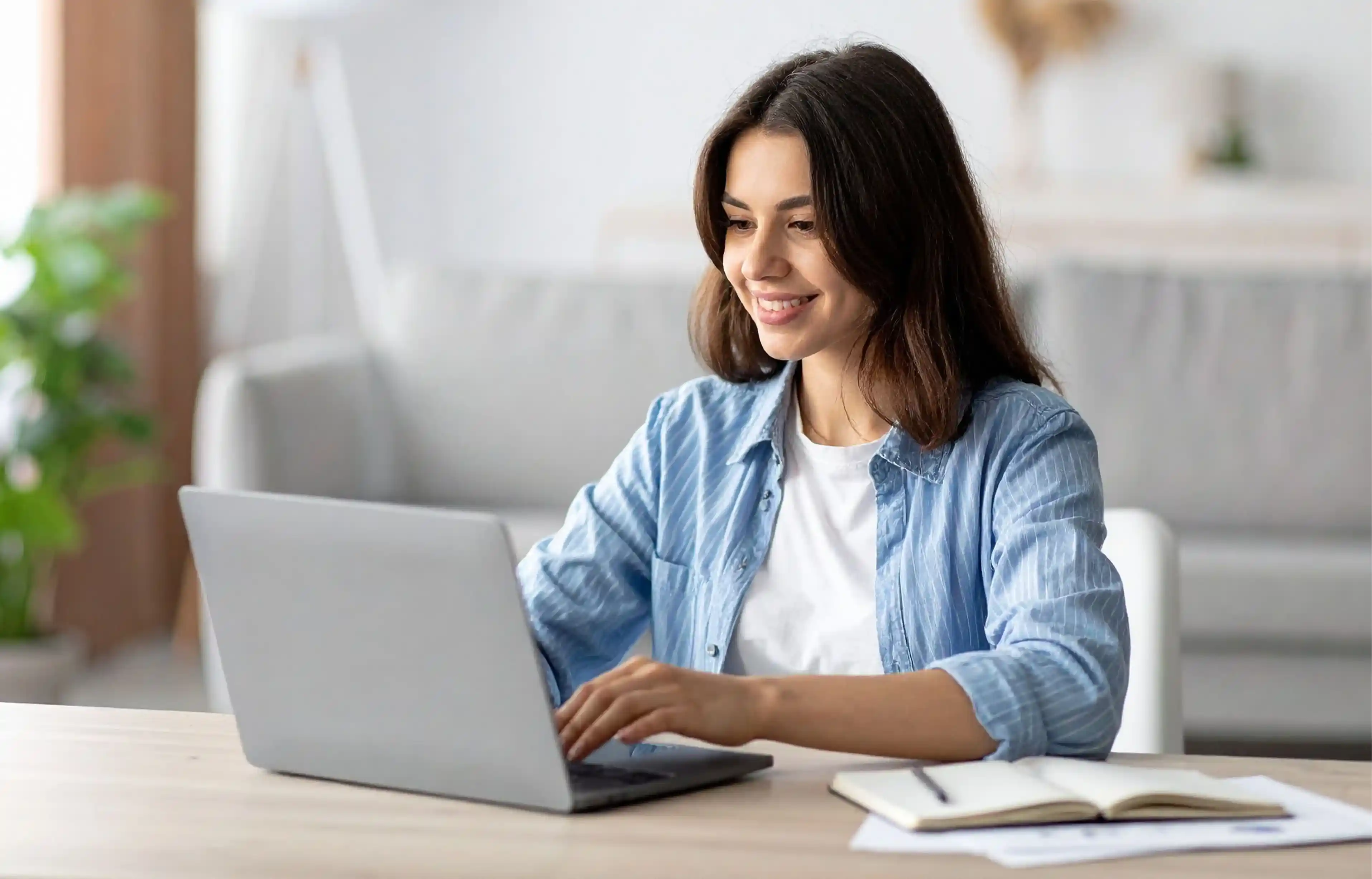 Remote employee working on a laptop in a bright home office.