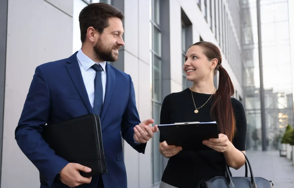 Two professionals discussing a job offer with no relocation assistance outside a modern office