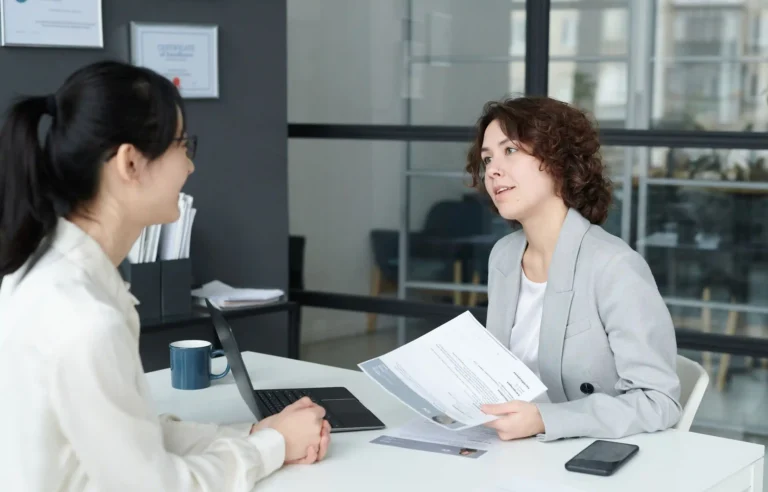 Two professionals discussing a job offer and relocation terms in an office.