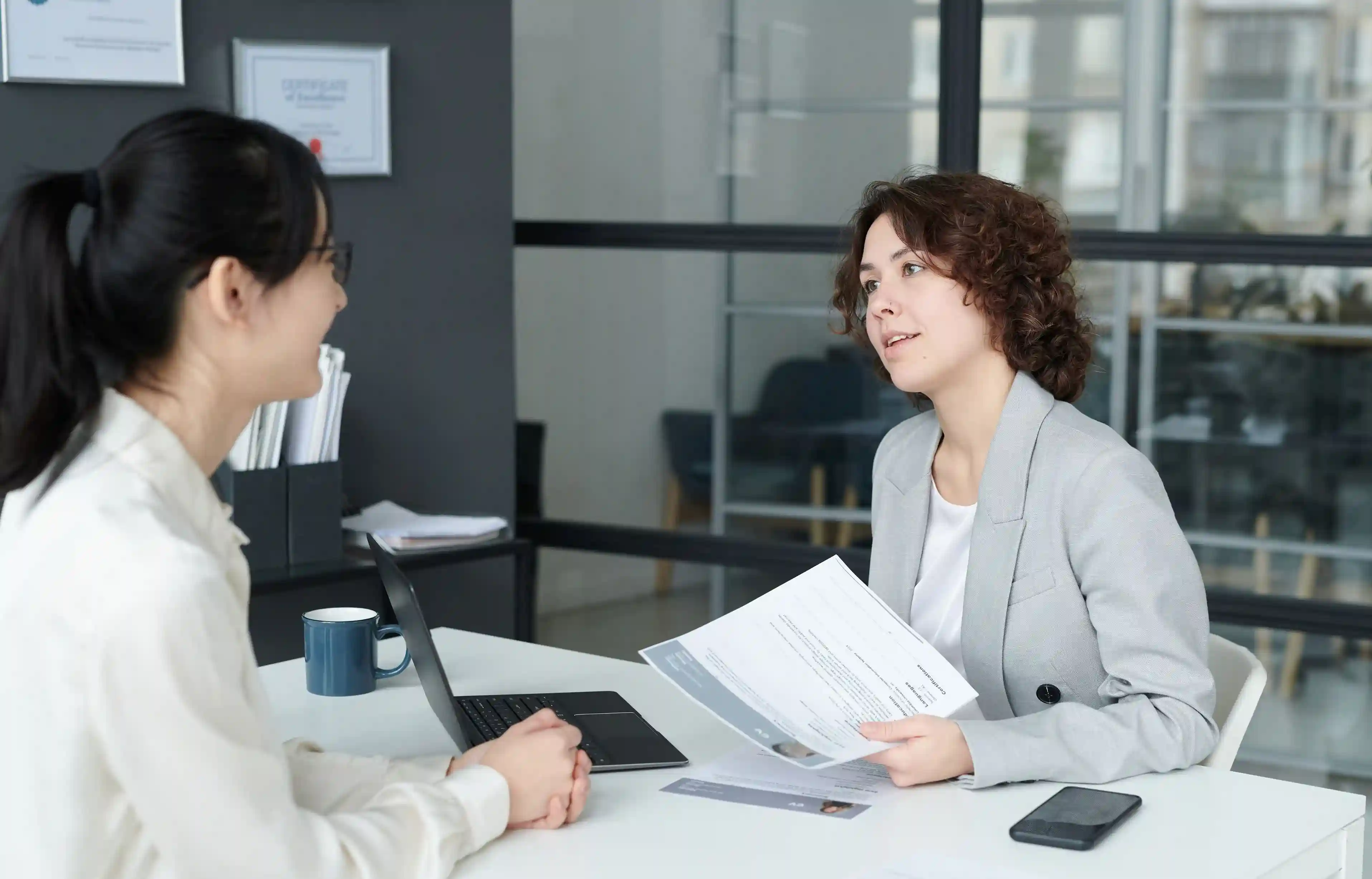 Two professionals discussing a job offer and relocation terms in an office.