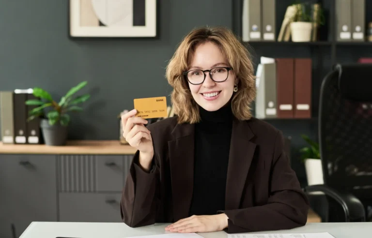 Woman holding a credit card while planning work relocation expenses in an office.