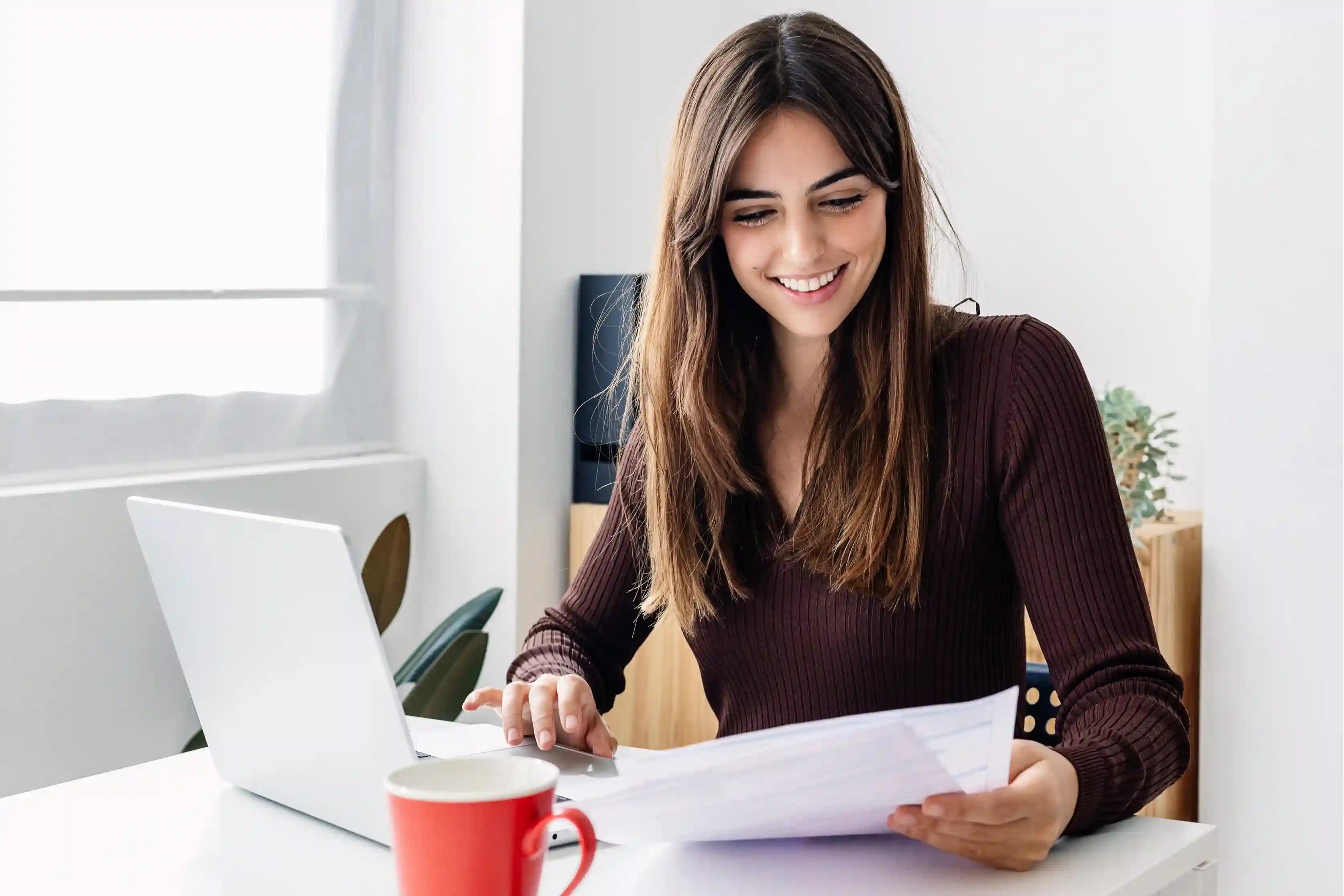 Woman reviewing paycheck documents at a home office after relocation.