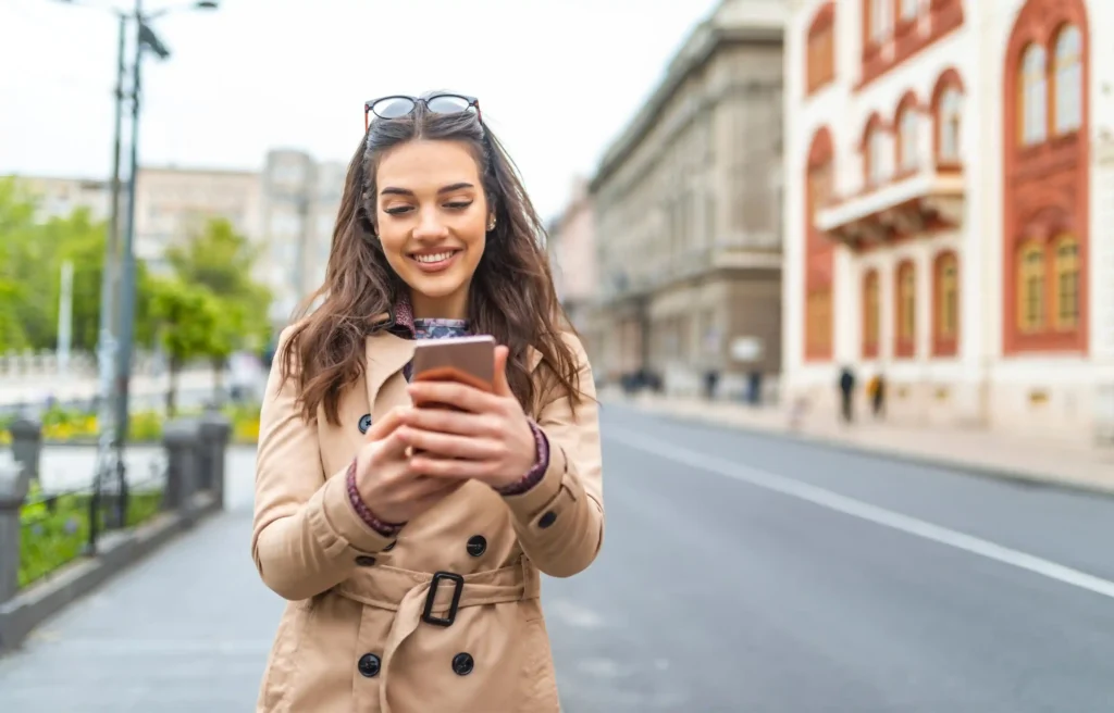 Woman using her phone while organizing documents to download before moving abroad and settling into life overseas.