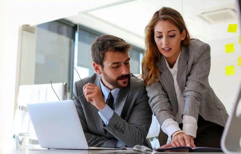 Business professionals reviewing relocation ROI and cost data together on a laptop in a modern office.
