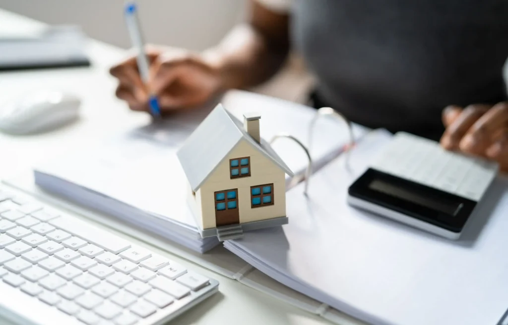 House model, calculator, and paperwork used to compare relocation property taxes and homeownership costs.