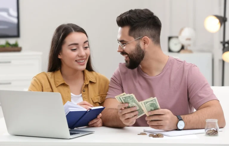 Couple reviewing cash and finances together beside a laptop.
