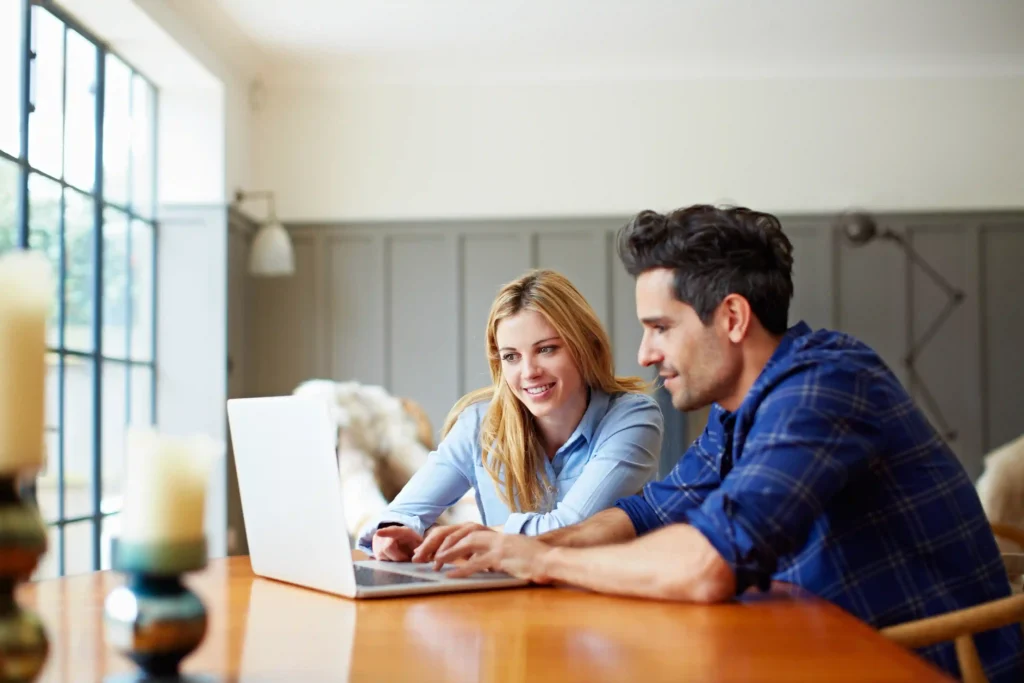 Couple reviewing a relocation benefit extension and move details together on a laptop in a bright, modern home.