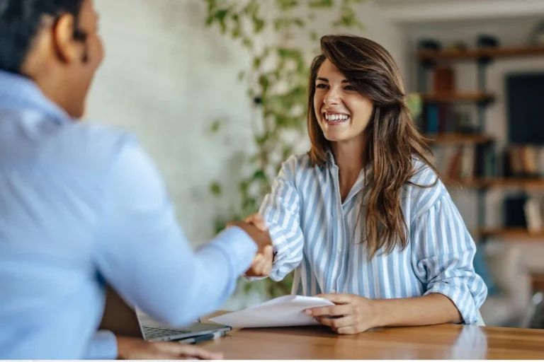 Employee shaking hands with a recruiter while discussing a job offer and relocation benefits.