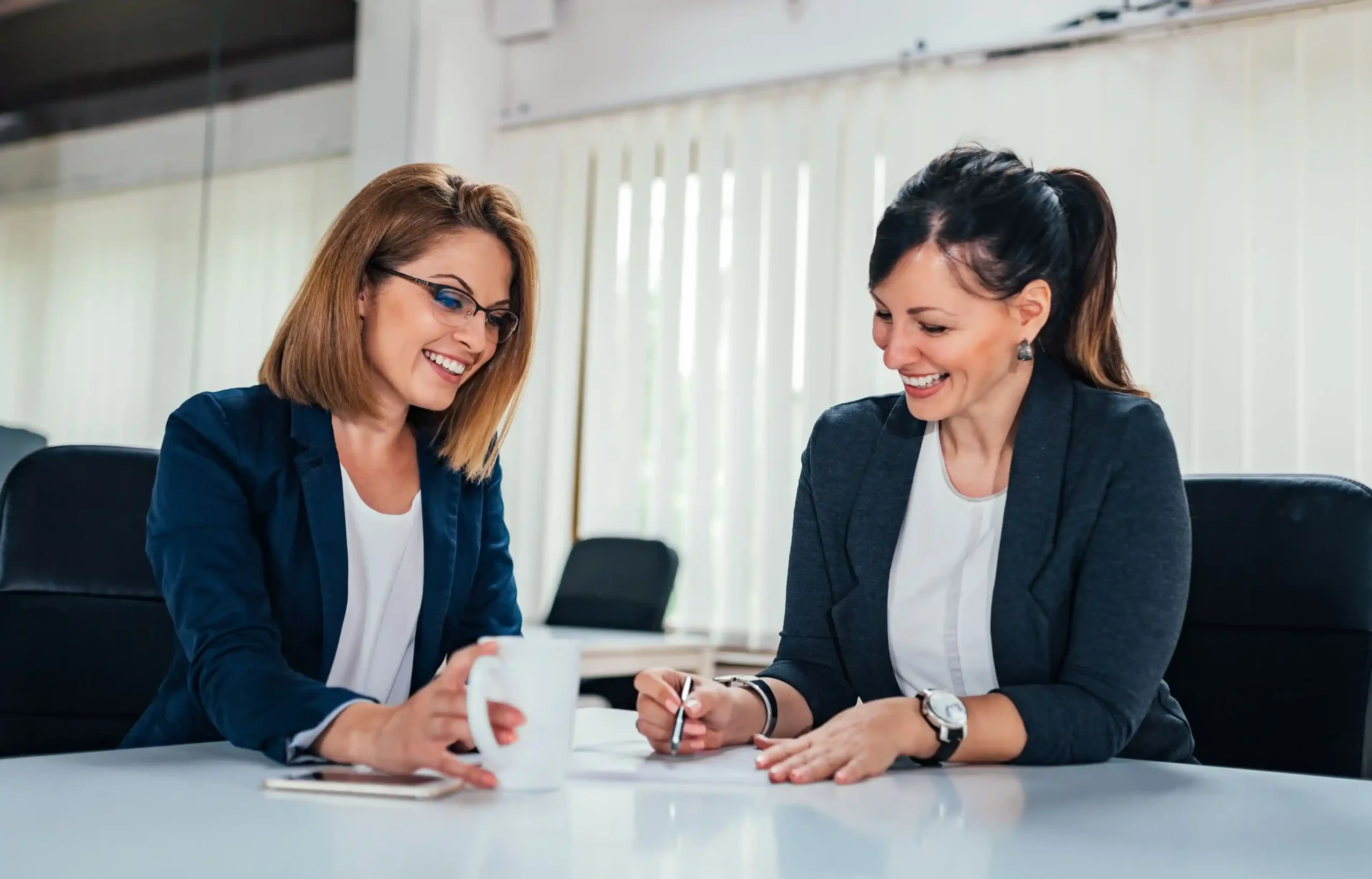 Employee signing relocation paperwork with an HR representative in an office.