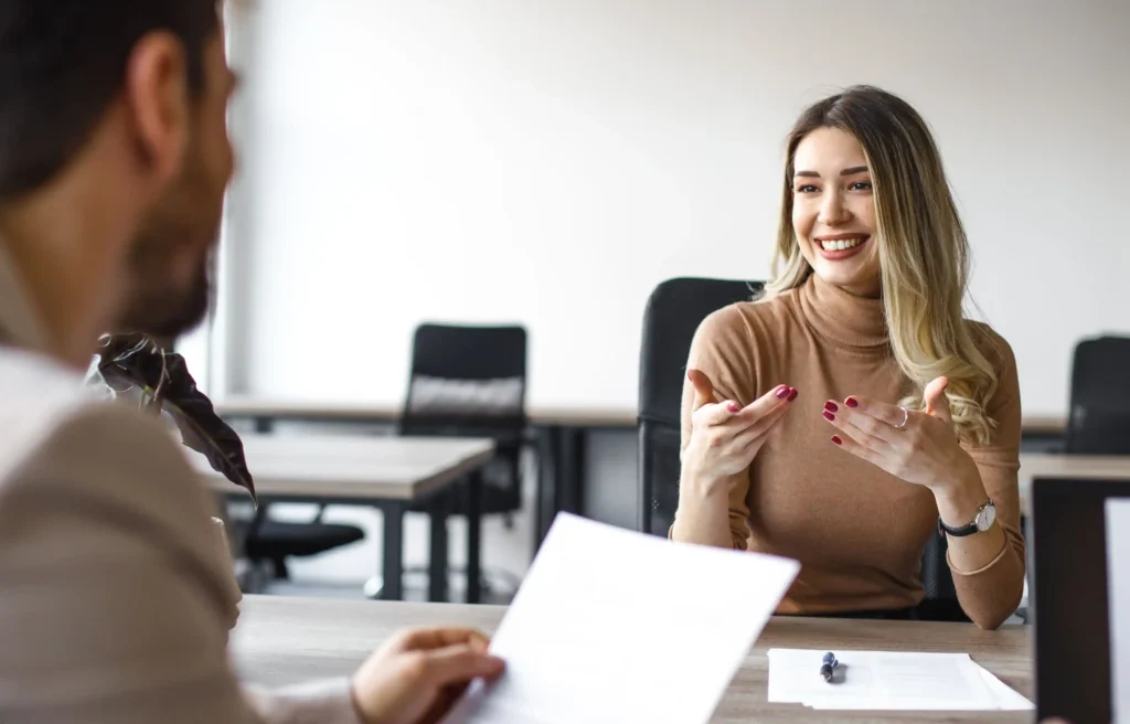 A job candidate speaks with an interviewer during a professional interview, illustrating how to get a job in another country.