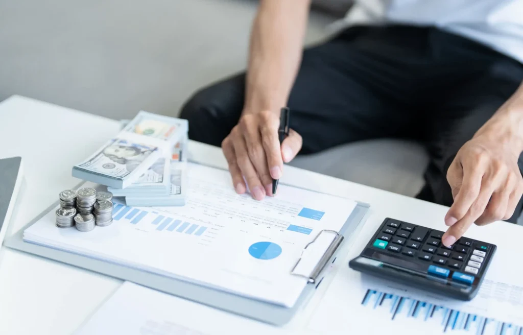 Professional reviewing the salary divide between AI and non-AI tech skills with charts, cash, and a calculator.