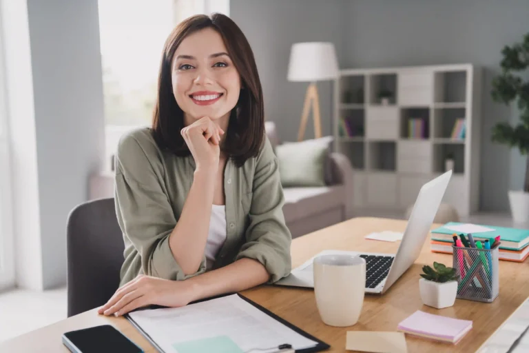 Remote employee working from home at a desk with a laptop in a bright home office.