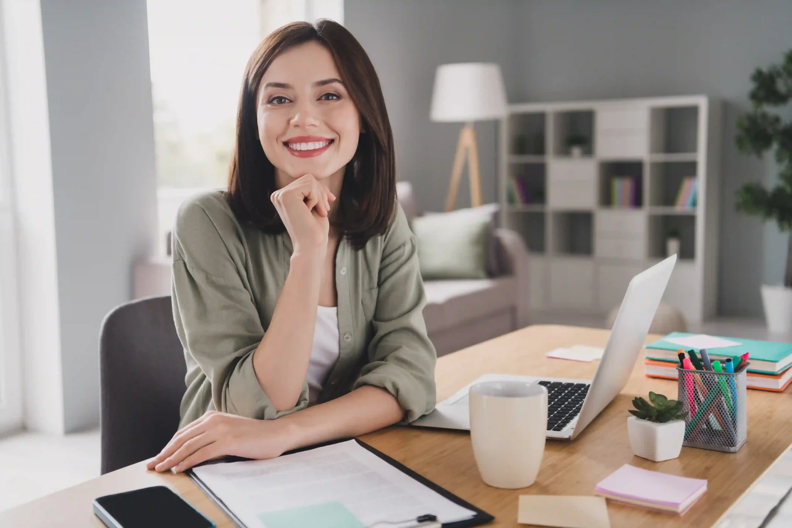 Remote employee working from home at a desk with a laptop in a bright home office.