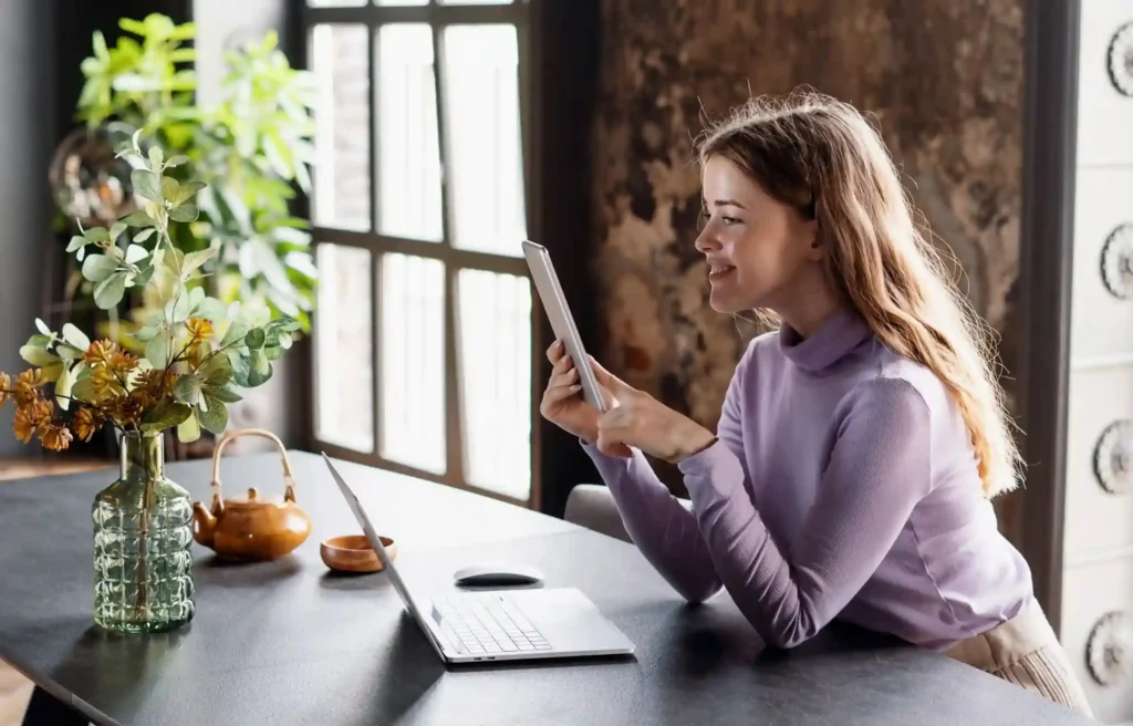 Remote work tax rules guide for a remote worker using a tablet beside her laptop in a bright home office.