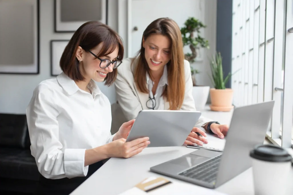 Two HR professionals reviewing relocation compensation details together on a tablet.