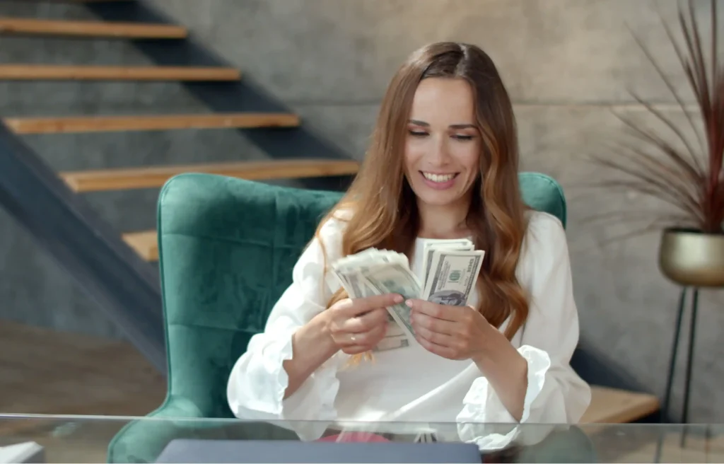 Woman counting cash from an unspent relocation stipend while reviewing money at home.