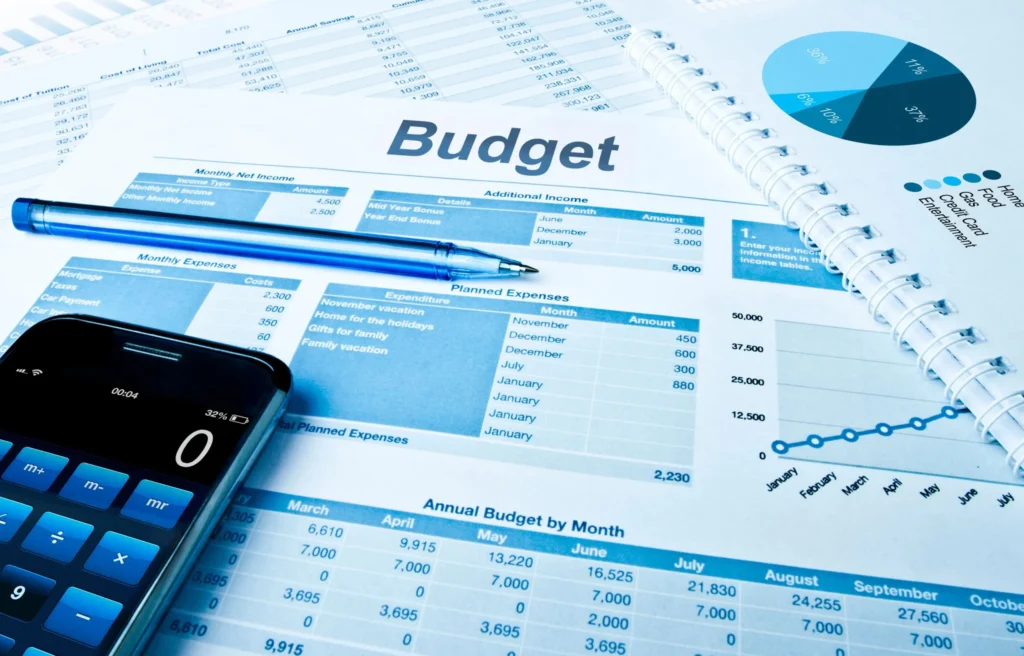 Budget planning documents, financial charts, and a calculator used to track relocation expenses and costs during a merger.