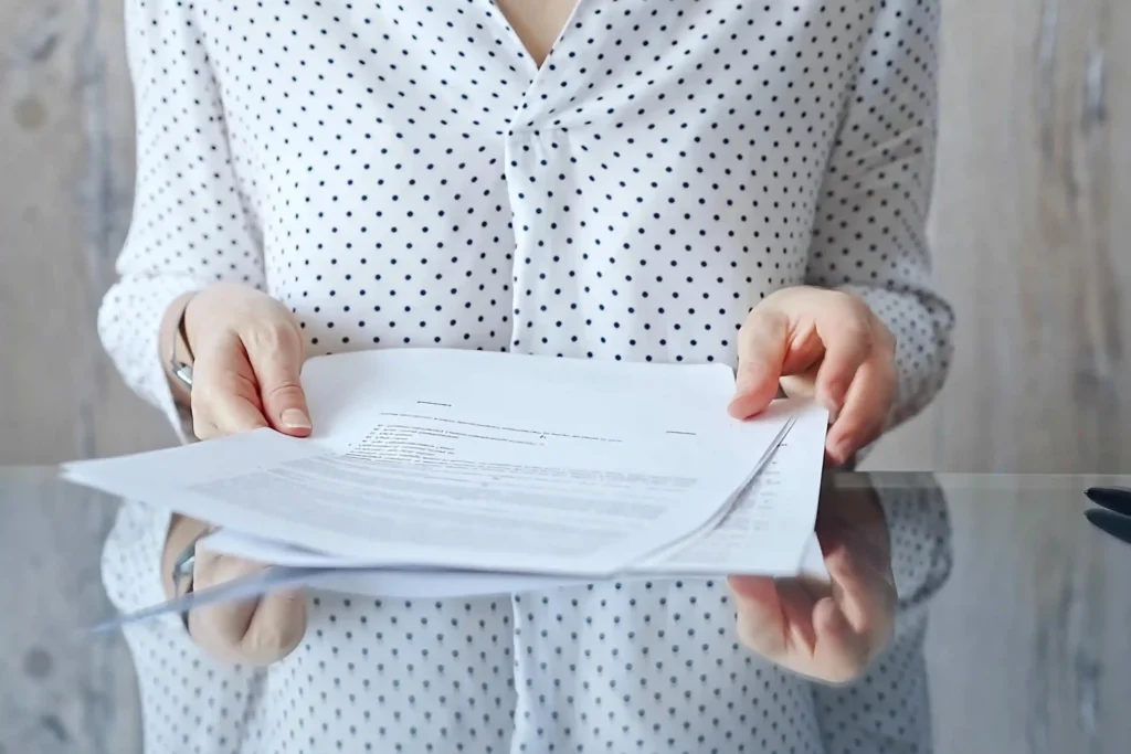 Employee holding relocation paperwork while reviewing job transfer and moving documents.