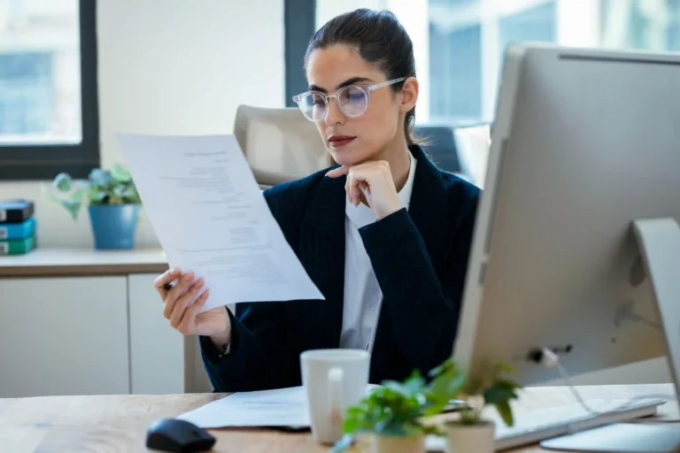 HR manager reviewing corporate relocation policy 2027 documents at her office desk.