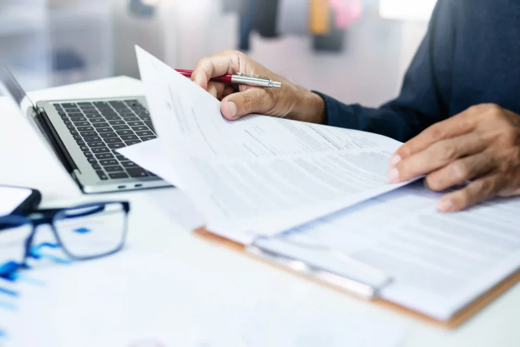 HR professional reviewing relocation policy 2027 documents and employee moving expenses beside a laptop.