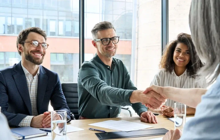Hiring manager shaking hands with a candidate during a job interview in a bright office.
