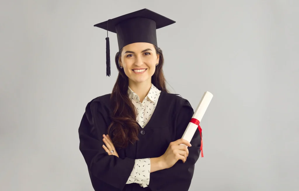 New graduate in cap and gown holding a diploma while preparing for new grad relocation packages and a first job.