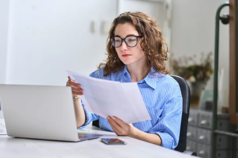 Woman reviewing job transfer documents beside a laptop before relocating to another state.