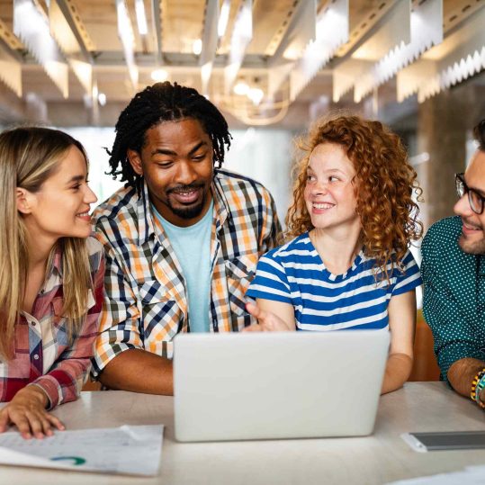 Happy employees collaborating in a modern office, reflecting the positive impact of an employee health benefit program.
